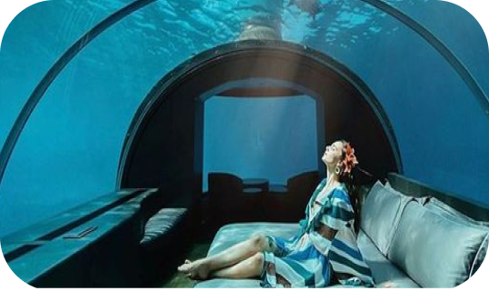 ragazza distesa a letto che guarda i pesci in una cupola sotto al mare